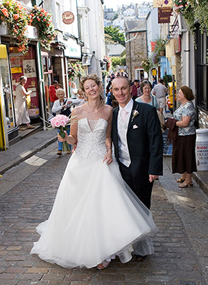 Bride and groom photographed walking through the cobbled streets of St Ives in Cornwall on the way to their wedding reception at the Tate gallery
